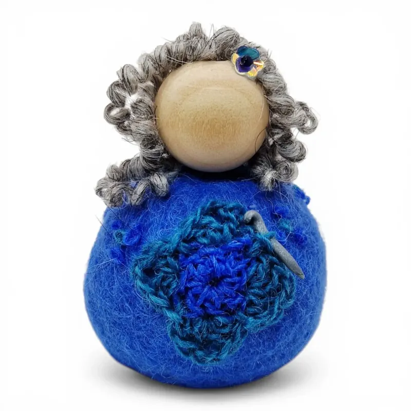 Handmade wool Crochet Lady Flóki wearing light blue dress holding a crochet needle. Iceland souvenir & gift.